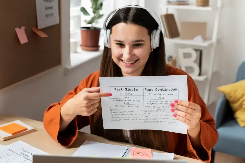 A girl holding a paper, studying tenses, wearing her white headphone in the room